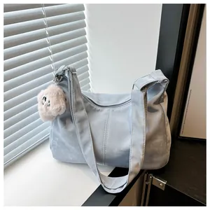 Detail of soft light blue tote bag with fuzzy dog charm against shuttered window