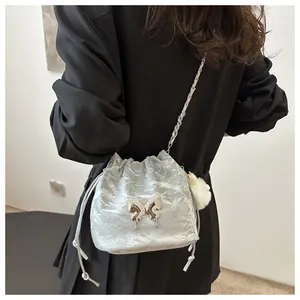 Silver drawstring bucket bag with metal butterfly clasp and chain strap on a model