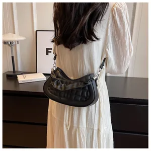 Detail view of black pleated crescent shoulder bag featuring square quilted texture