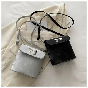 Detalle de bolsos bandolera elegantes con lazo metálico y acabado de terciopelo gris y negro