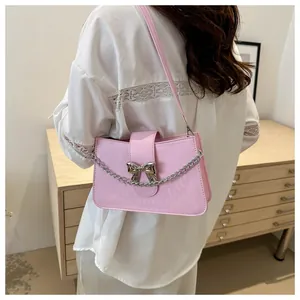 Detail of pink PU leather bag featuring a silver metal bow buckle and decorative chain