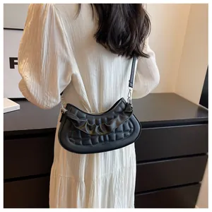 Model view of black quilted half-moon shoulder bag with pleated details and silver buckles