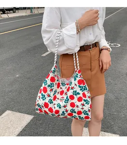 Close-up of floral canvas tote bag with red roses and striped rope handle detail