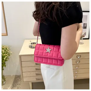 Detail of pink quilted crossbody bag with silver star ornament and chain strap