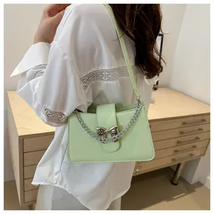 Detail of mint green crossbody bag with silver bow accent and chunky chain strap