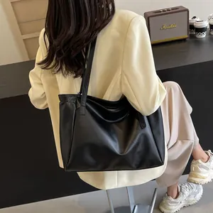 Grand sac cabas noir minimaliste en similicuir porté par un mannequin en tenue décontractée