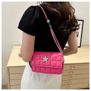Detail of bright pink quilted bag with silver star and chain strap on a model
