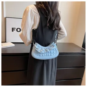 Close-up of light blue quilted crossbody bag with stylish ruched handle and silver metal rings