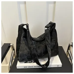 Detail of black distressed leather hobo bag with wide strap on a white book display