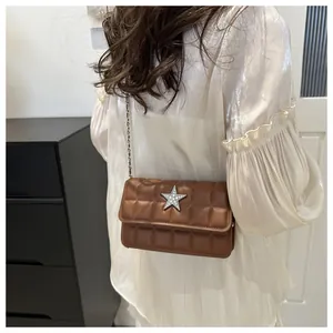 Detail shot of brown quilted crossbody bag with a silver rhinestone star on the front