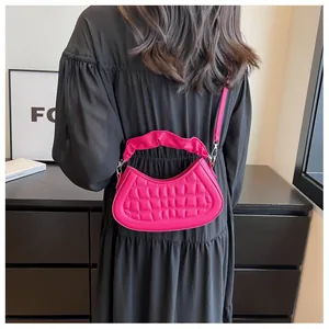Detailed back view of a bright pink quilted crescent bag with ruffled handle worn by a model