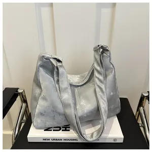 Detail of silver metallic hobo bag with marble texture finish on white books