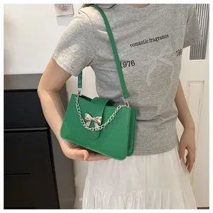 Close-up of vintage green leather handbag featuring a silver metal bow buckle and chain