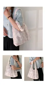 Détail de la broderie papillon en dentelle rose et franges sur le sac cabas en toile blanc