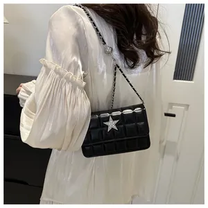 Close-up of black quilted leather crossbody bag with star rhinestone and chain strap