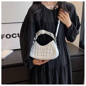 Detailed view of a white quilted crescent bag with ruffled handle and silver hardware