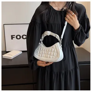 Close-up of white crescent bag with quilted texture and ruched handle detail