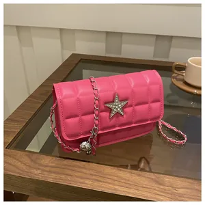 Detail of bright pink quilted crossbody bag with rhinestone star and silver chain strap