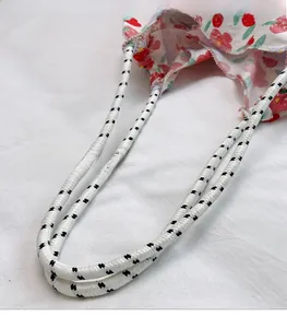 Detail of sturdy braided rope handles on white fabric bag with fresh strawberry print