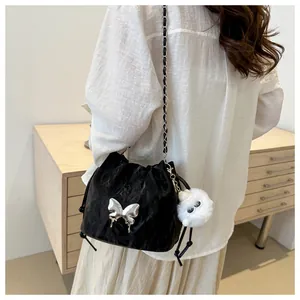 Detail of black drawstring bucket bag with silver Y2K bow and plush charm