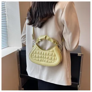 Detail of light yellow quilted crescent bag with ruffled handle and silver hardware