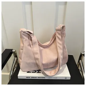 Detail of soft pink large capacity tote bag with adjustable strap on a leather chair
