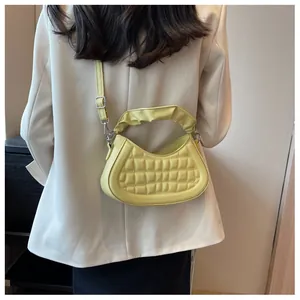 Detail of yellow pleated handle bag with checkered quilted pattern on white suit