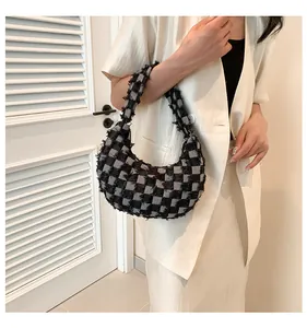 Detail of checkered canvas hobo bag with frayed edges worn by a model in a stylish setting