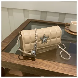 Detailed view of beige quilted handbag featuring a sparkling star metal buckle and chain strap