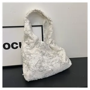 Détail d'un sac cabas en toile blanche avec broderie papillon argentée et texture douce