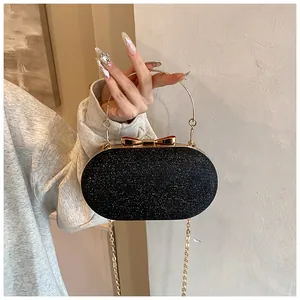 Detail of black glitter clutch with gold bow clasp and metallic circular handle