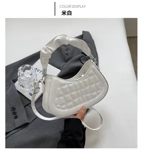 Top view of off-white quilted handbag with ruched handle and detachable strap on suit