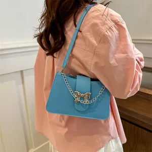 Chic light blue shoulder bag with silver chain and bow buckle worn by a model
