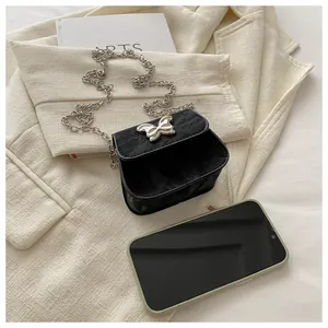 Close-up of black mini crossbody bag with silver butterfly lock and metal chain strap