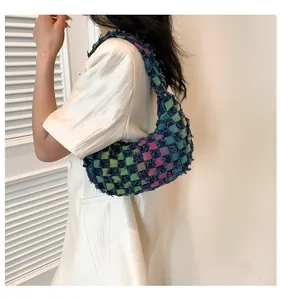 Detail of colorful checkered canvas baguette bag with fringed edges and gradient pattern