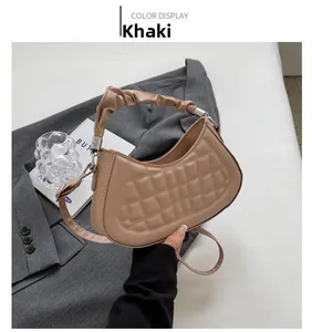 Detail of khaki pleated handle handbag with quilted texture on grey blazer