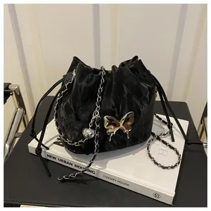 Close-up of black drawstring bucket bag with silver butterfly pendant and metal chain