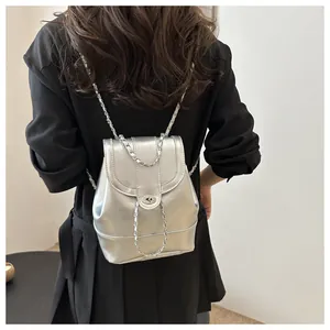 Detail eines silbernen PU-Rucksacks mit Drehverschluss und gewebten Kettenriemen