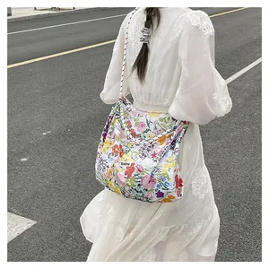 Detailed back view of a floral canvas tote bag with woven rope straps on a street scene
