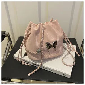 Detailed view of pink marble drawstring bucket bag with silver butterfly metal charm