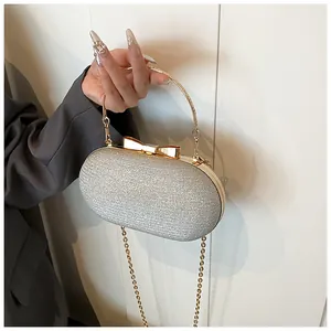 Detail of silver sequin evening clutch with golden bow clasp and metal handle