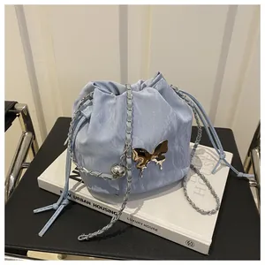 Detail of light blue bucket bag featuring pleated texture and silver butterfly ornament