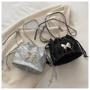 Close-up of drawstring bucket bags with metallic butterfly buckles and chain straps