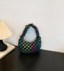 Detail of multi-color plaid canvas handbag with fringe edges and patchwork design