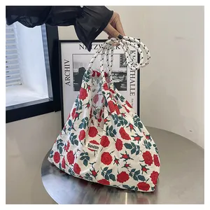 Detail of floral canvas tote bag featuring red roses and thick nylon rope handles