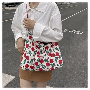 Detail of floral tote bag showing vibrant red rose pattern and canvas shoulder strap