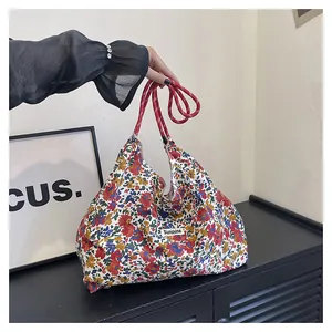 Detail of floral canvas tote bag featuring red braided rope handle and Sunshine label