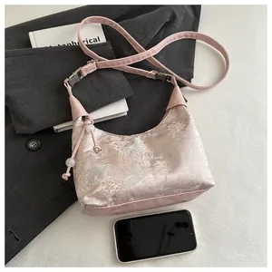 Détail du sac en satin rose avec broderie chinoise et pompons décoratifs en perles