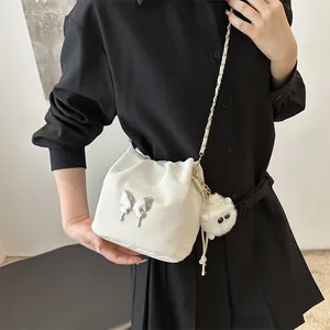 White pleated bucket bag with silver butterfly emblem and cute plush monster charm
