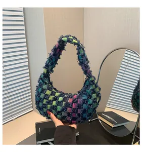 Close-up of bohemian checkered woven handbag with fringe trim and crescent shape
